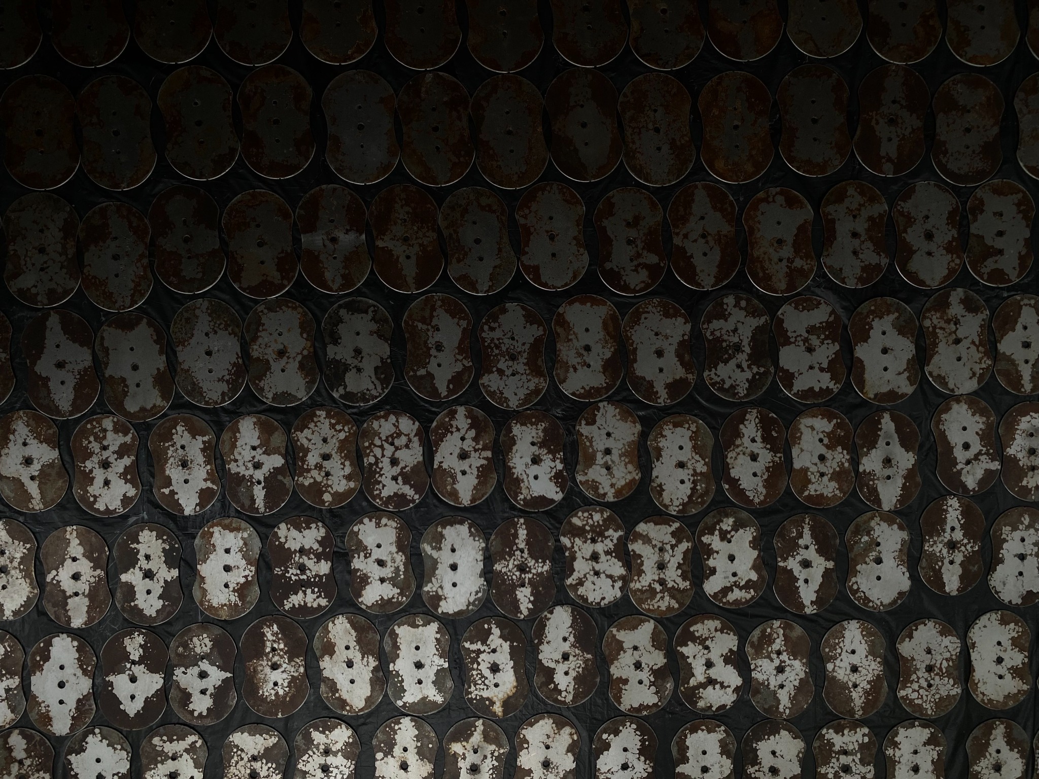 Rows of shaped steel plates showing clean sound-wave patterns against rusted surfaces.